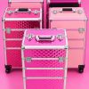 Maletines profesionales de manicura y estética en tonos rosas, con ruedas, cierres metálicos y diseños geométricos, ideales para transportar productos y herramientas de belleza.
